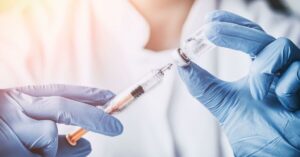 A doctor with a syringe and vial of peptide therapy.