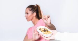 Woman refusing a plate of nuts because of her food sensitivity.