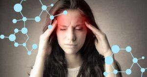 Woman suffering from long covid symptoms, holding her hands to her head.